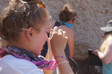 Emily using her hand lense to identify minerals in pumice
